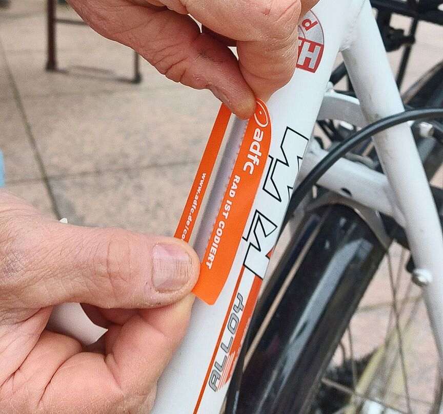 Am 16. Juli wird der ADFC Ettlingen in der Altstadt wieder Fahrräder codieren Ein ADFC-Helfer versieht den Code am Fahrradrahmen mit einer Schutzfolie