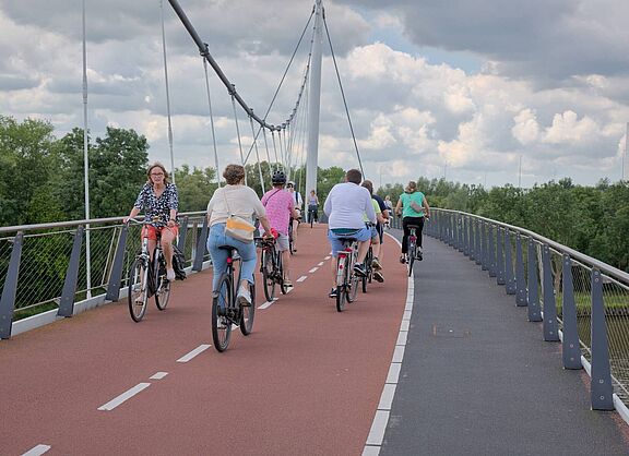 Foto mit Blick auf den getrennten Geh- und Radweg auf der Nesciobrug in Amsterdam. Radfahrende fahren dem Fotografen entgegen und von ihm weg.