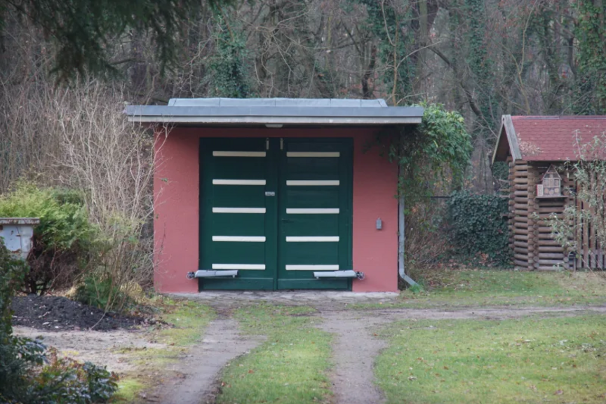 eine Garage Foto einer einzeln stehenden Garage, die zurückgesetzt in einem Grundstück steht