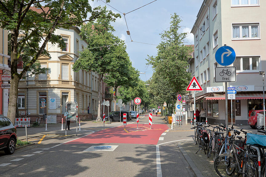 Modaler Filter Sophienstraße/Lessingstraße mit Abbiegegebot Foto der Diagonalsperre an der Kreuzung Sophienstraße/Lessingstraße in Karlsruhe. Blick von Osten entlang der Sophienstraße. Der Fotograf steht am rechten Fahrbahnrand. Rechts im Bild stehen mehrere Fahrradständer.