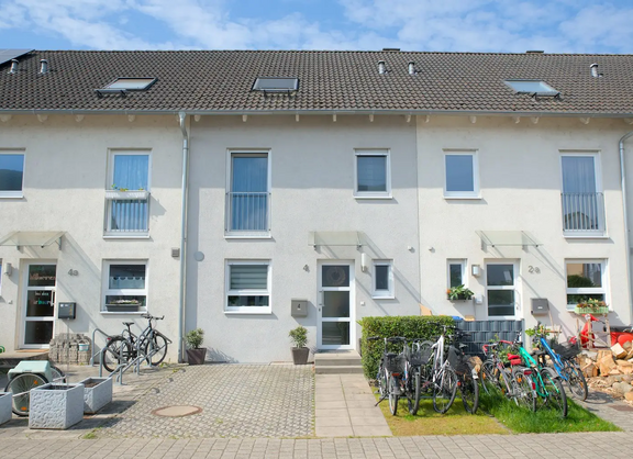 Foto eines schmalen Einfamilien-Reihenhauses in Knielingen Nord. Im Vorgarten ist ein Kfz-Stellplatz angelegt, daneben befindet sich ein kleiner Fahrradständer.