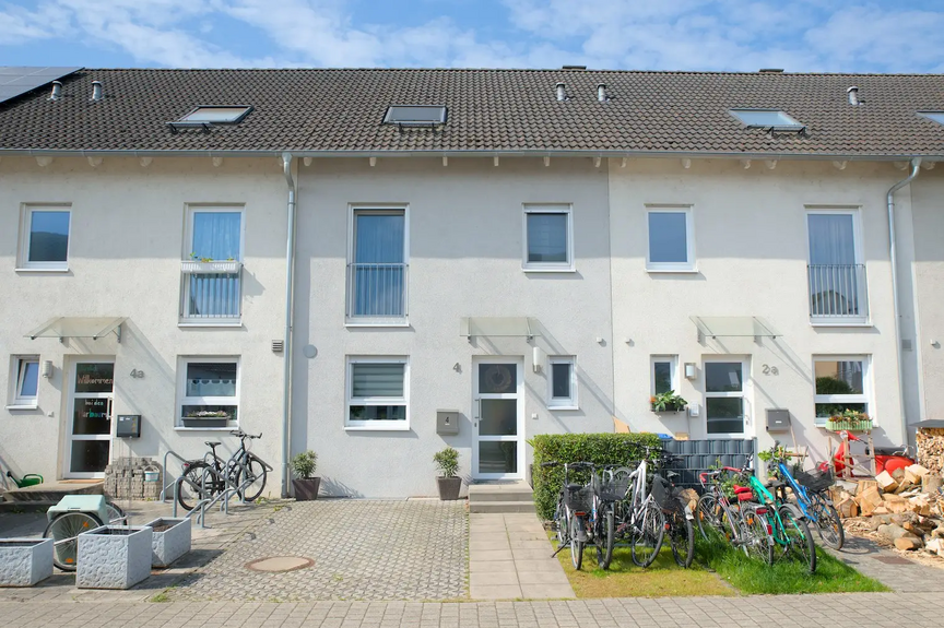 Foto eines schmalen Einfamilien-Reihenhauses in Knielingen Nord. Im Vorgarten ist ein Kfz-Stellplatz angelegt, daneben befindet sich ein kleiner Fahrradständer.