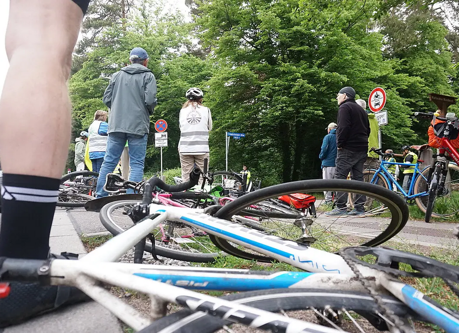 Ride of Silence am 21. Mai 2025 in Karlsruhe, Bikedown am Adenauerring Fahrräder liegen symbolisch an der Einmündung Adenauerring/Friedrichstaler Allee auf dem Boden. Blick aus Knöchehöhe. Im Hintergrund spricht eine Rednerin.